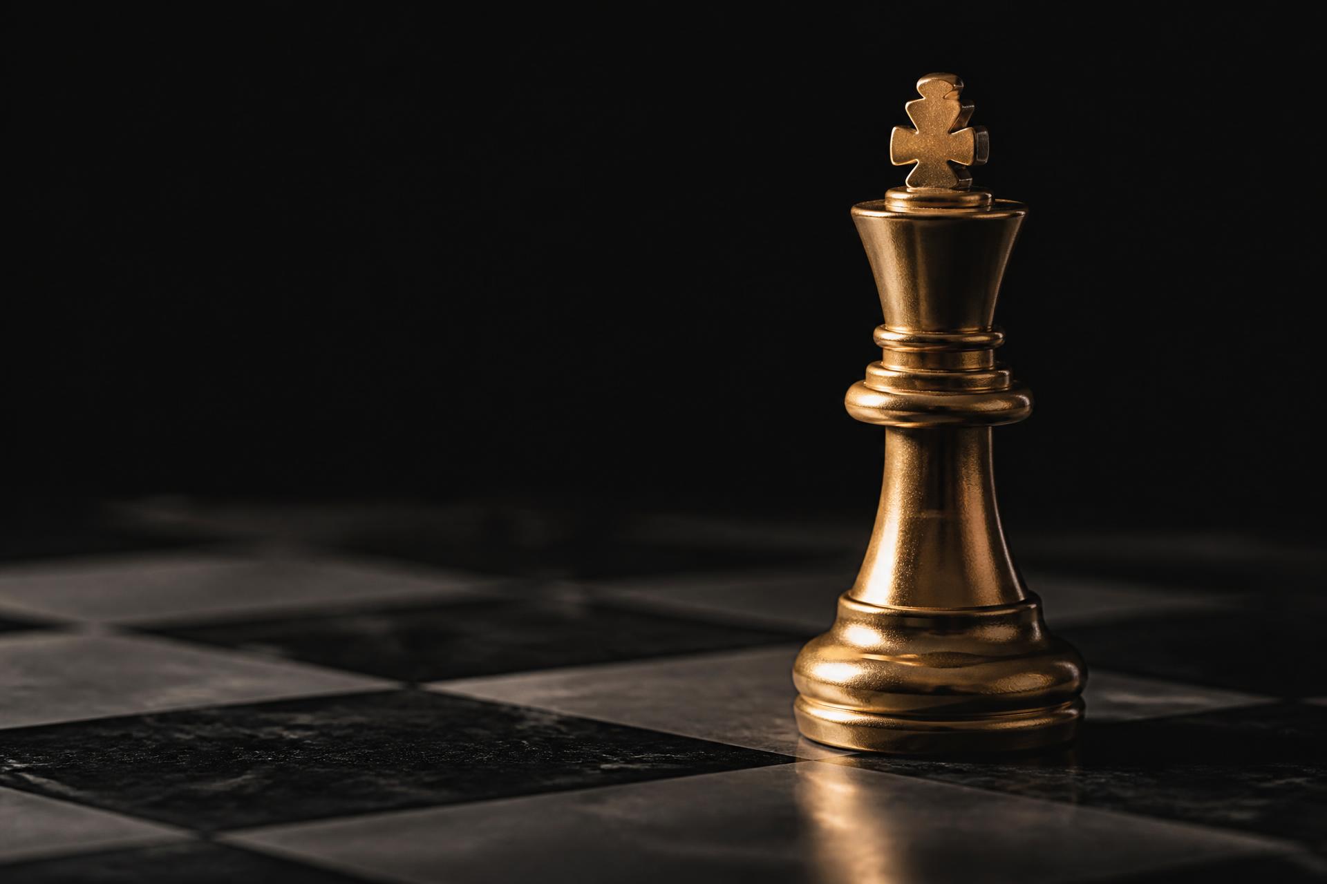 A gold king on a black marble chessboard — read the position before making the first move.